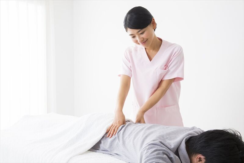 男性の腰を施術する女性スタッフ
